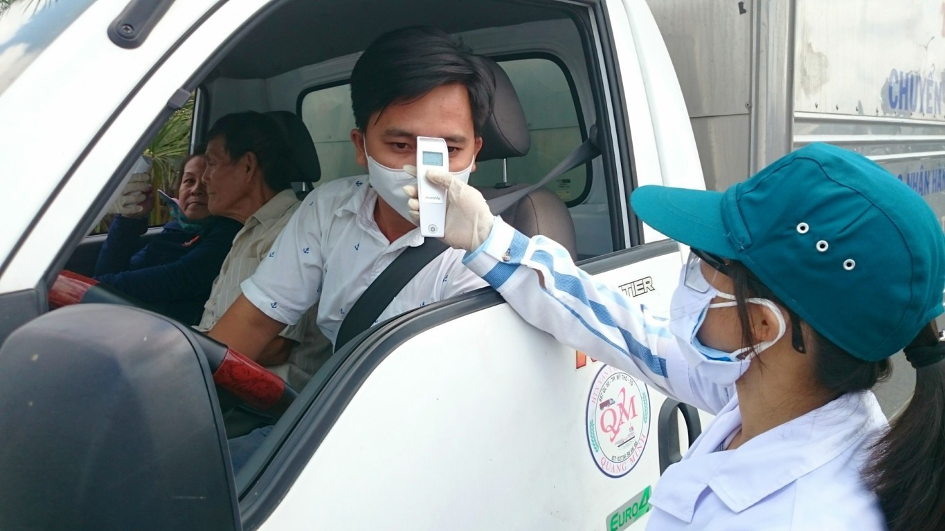 Nhân viên y tế đang kiểm tra đo thân nhiệt người điều khiển phương tiện giao thông đường bộ lưu thông vào nội ô thành phố Cần Thơ. Ảnh: Thái Bình